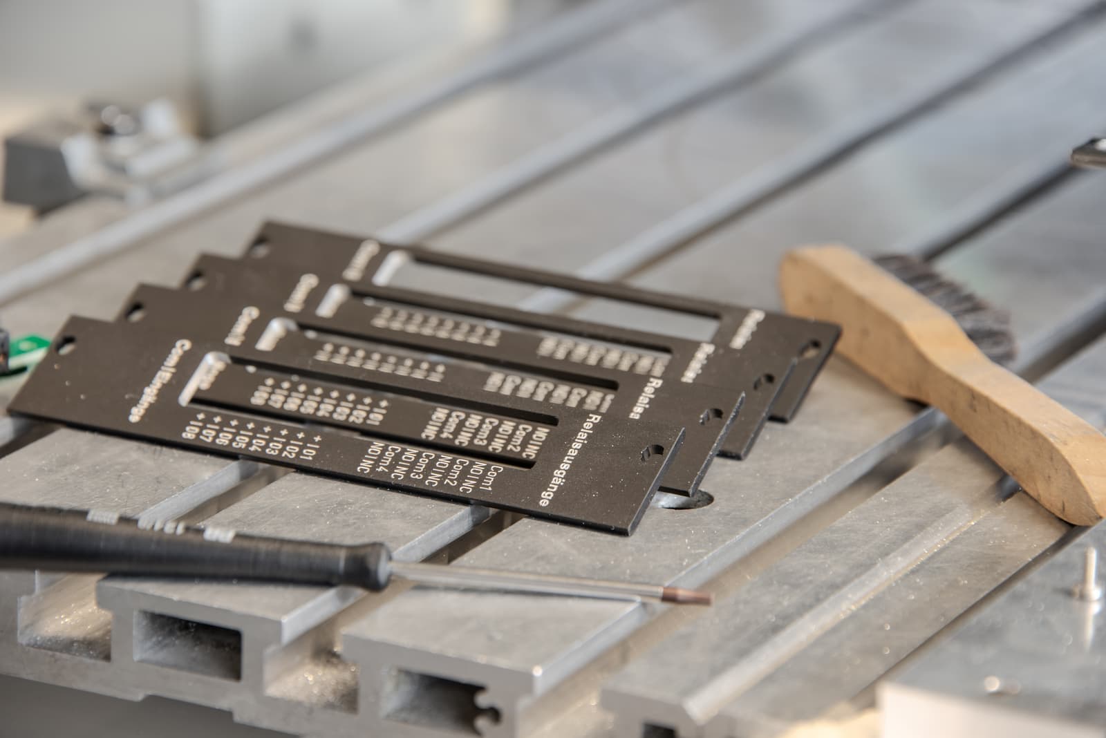 Gravierte Rückplatten aus schwarz eloxiertem Aluminium auf dem Maschinentisch